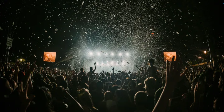 Concert audience under stage lights as confetti fills the arena.