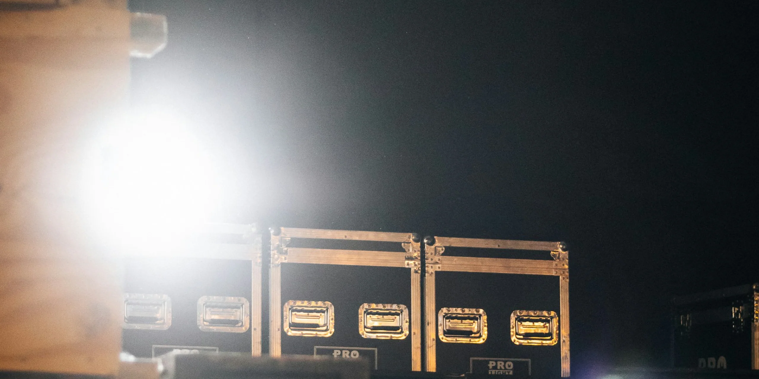Stacked road cases caught in a single hard light backstage.